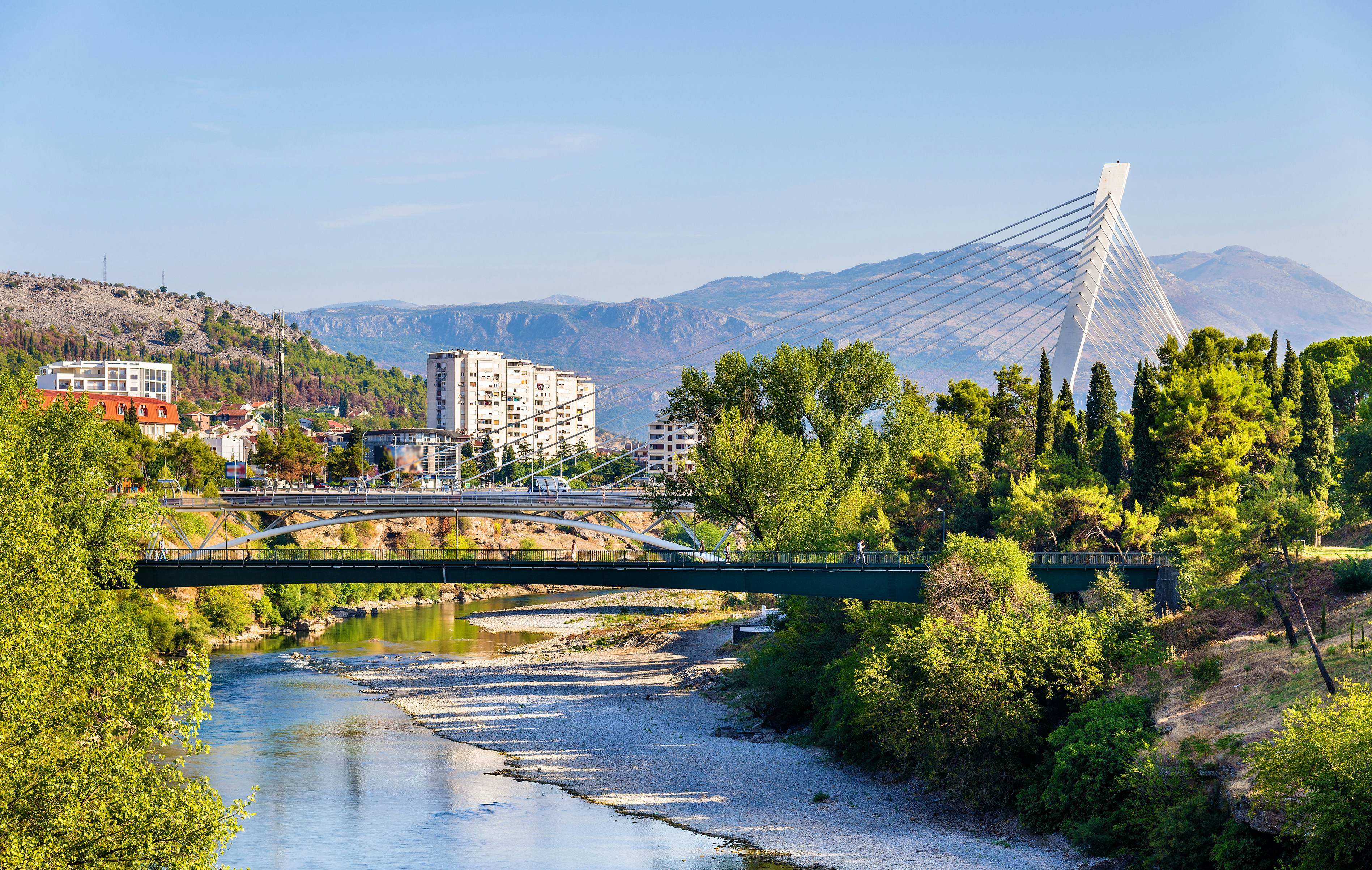 Podgorica’s scenic riverside with its modern and traditional bridges, surrounded by greenery and mountains.