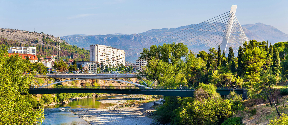 Podgorica’s scenic riverside with its modern and traditional bridges, surrounded by greenery and mountains.